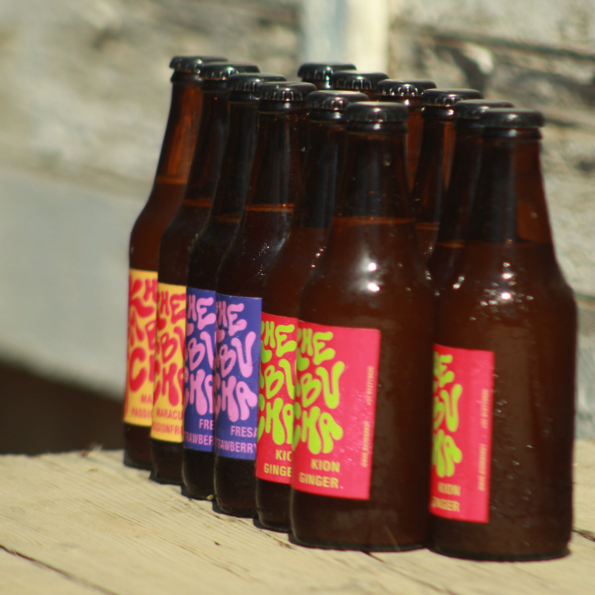 Pack de 12 kombuchas Khe en botellas de vidrio ámbar, bebidas fermentadas artesanales con cultivos vivos y sabores naturales.